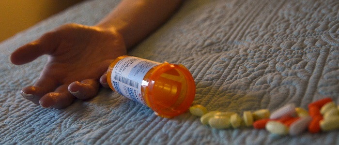 Picture of an empty hand, pill bottle, and pills on the floor