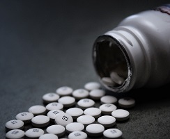 Opioid pills partially poured from prescription bottle