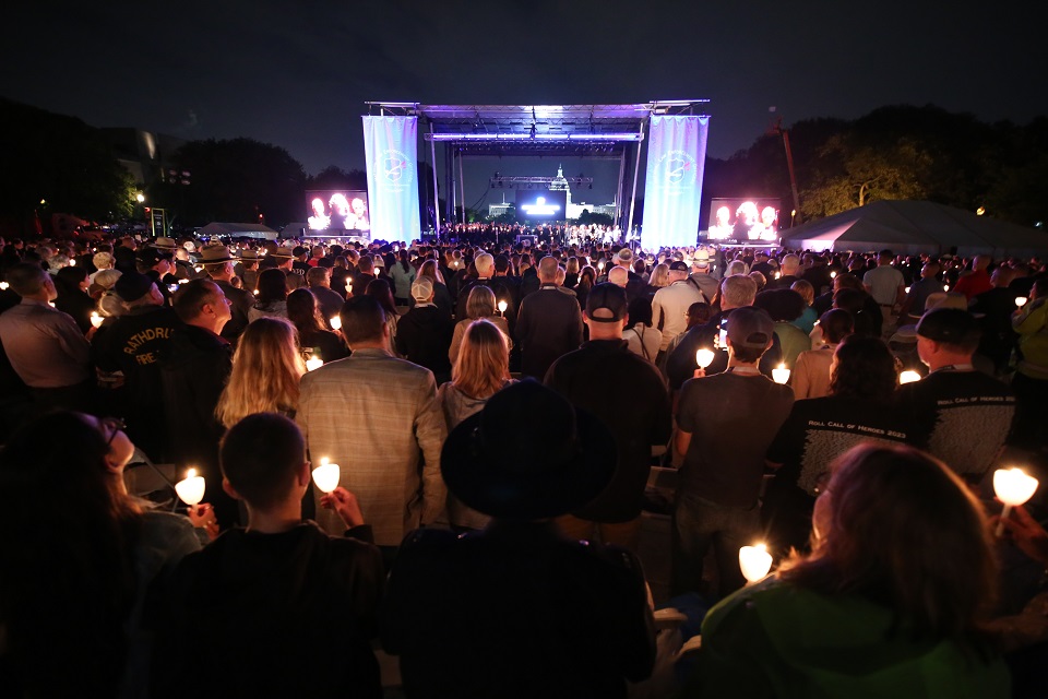 night scene with crowd holding lit candles facing lighted stage