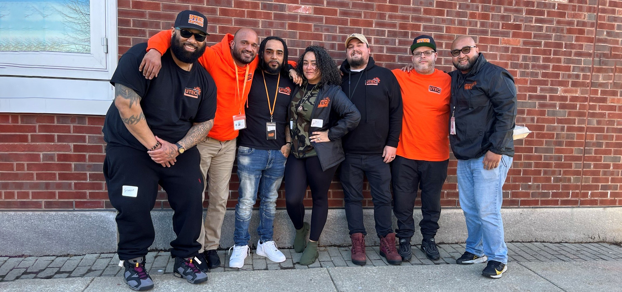 Group of adults posing in front of a brick wall