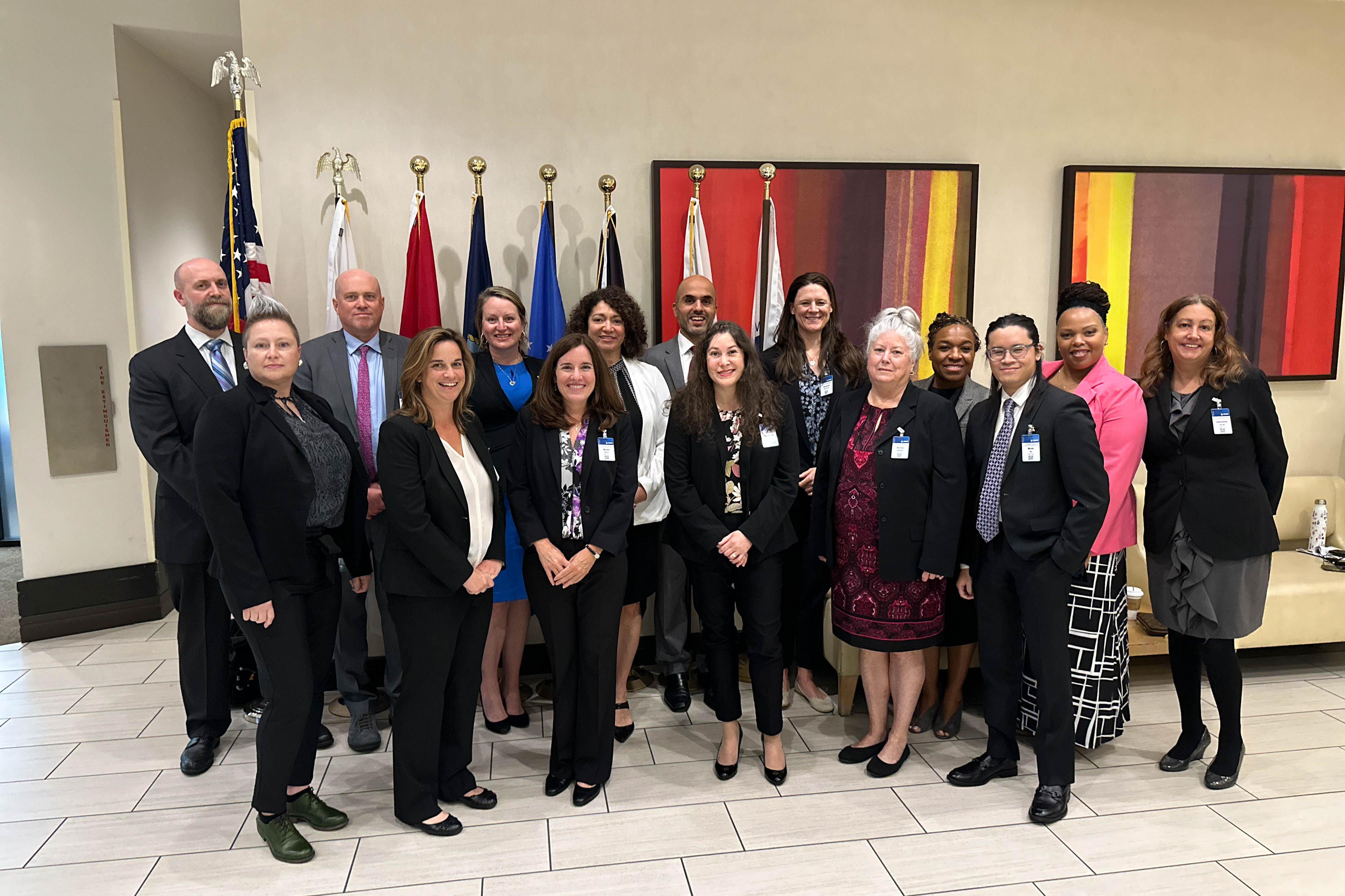 Group photo of SMART Office staff in front of wall with standing flags and art