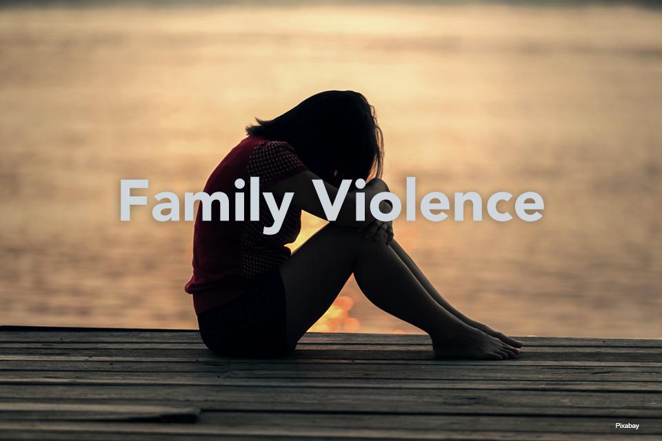 Family Violence with woman sitting with head in crossed arms on a dock in front of water