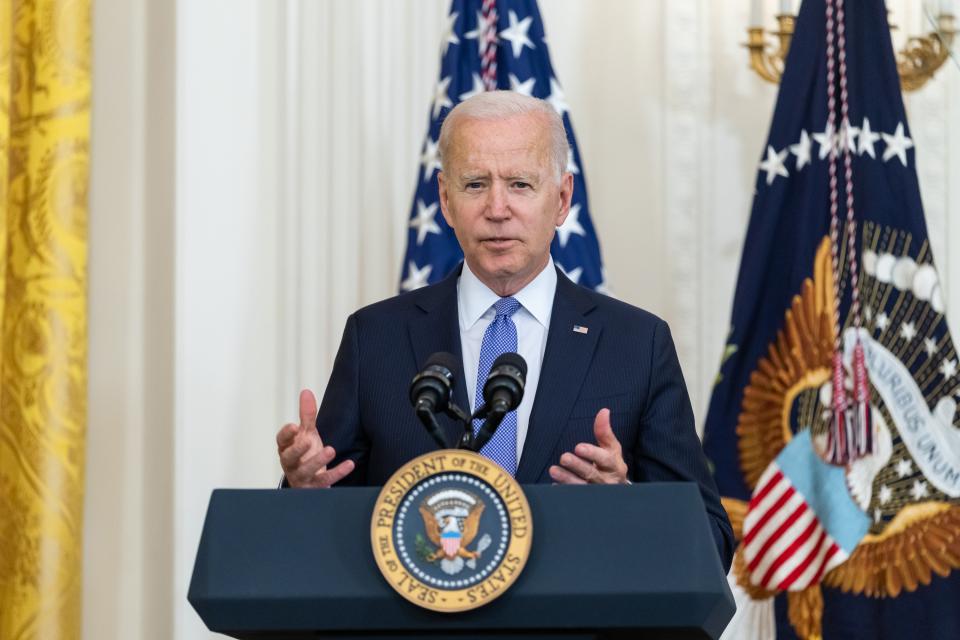 An older man with short white hair wearing a dark blue suit and light blue tie, speaking at a podium with the Presidential seal in a formal White House setting.