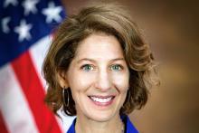 Amy Solomon smiles in front of U.S. Flag in background