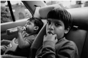 Photograph of anxious children in the back seat of an automobile.