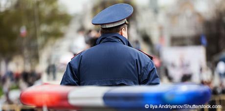 Image of police officer with police vehicle lights in background